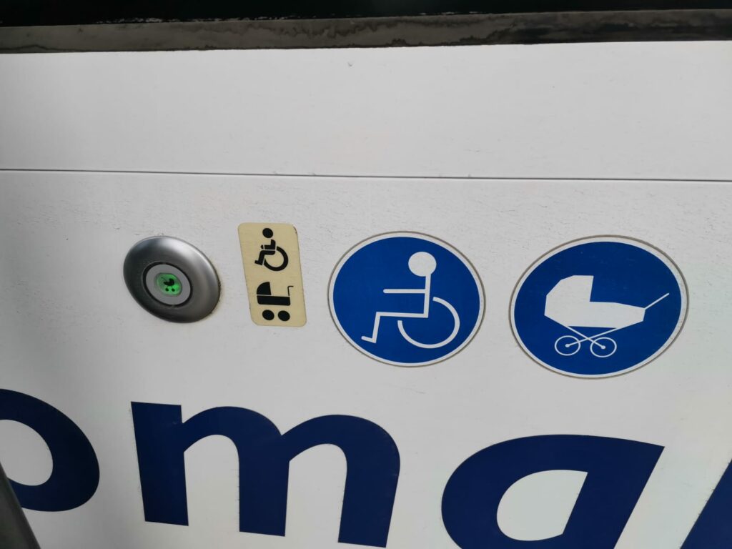 Wheelchair and pram buttons by the door of the bus.